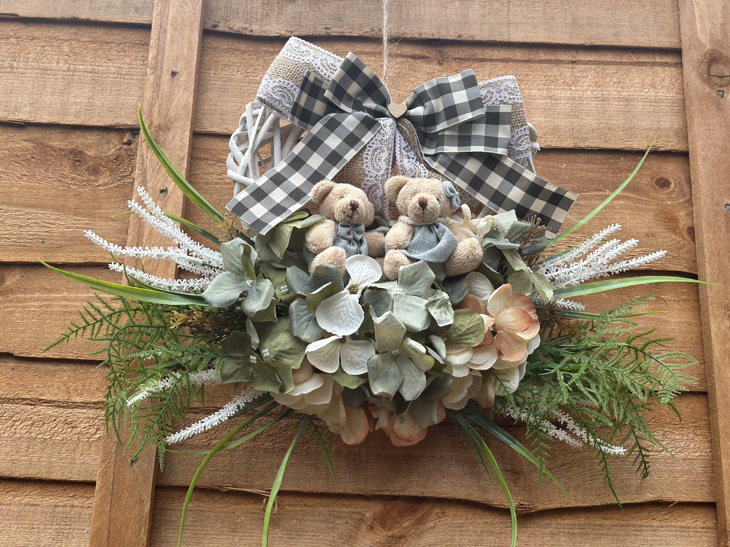 "Handmade heart-shaped wreath with teddy bears, artificial flowers, and a rustic burlap bow. Vintage-style home decor, perfect for housewarming gifts, nursery decoration, and front door wreaths. Romantic and family-inspired wooden wreath for indoor and outdoor use."