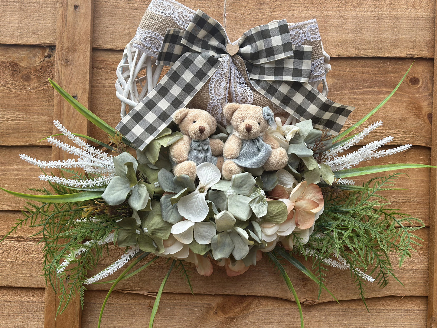 "Handmade heart-shaped wreath with teddy bears, artificial flowers, and a rustic burlap bow. Vintage-style home decor, perfect for housewarming gifts, nursery decoration, and front door wreaths. Romantic and family-inspired wooden wreath for indoor and outdoor use."