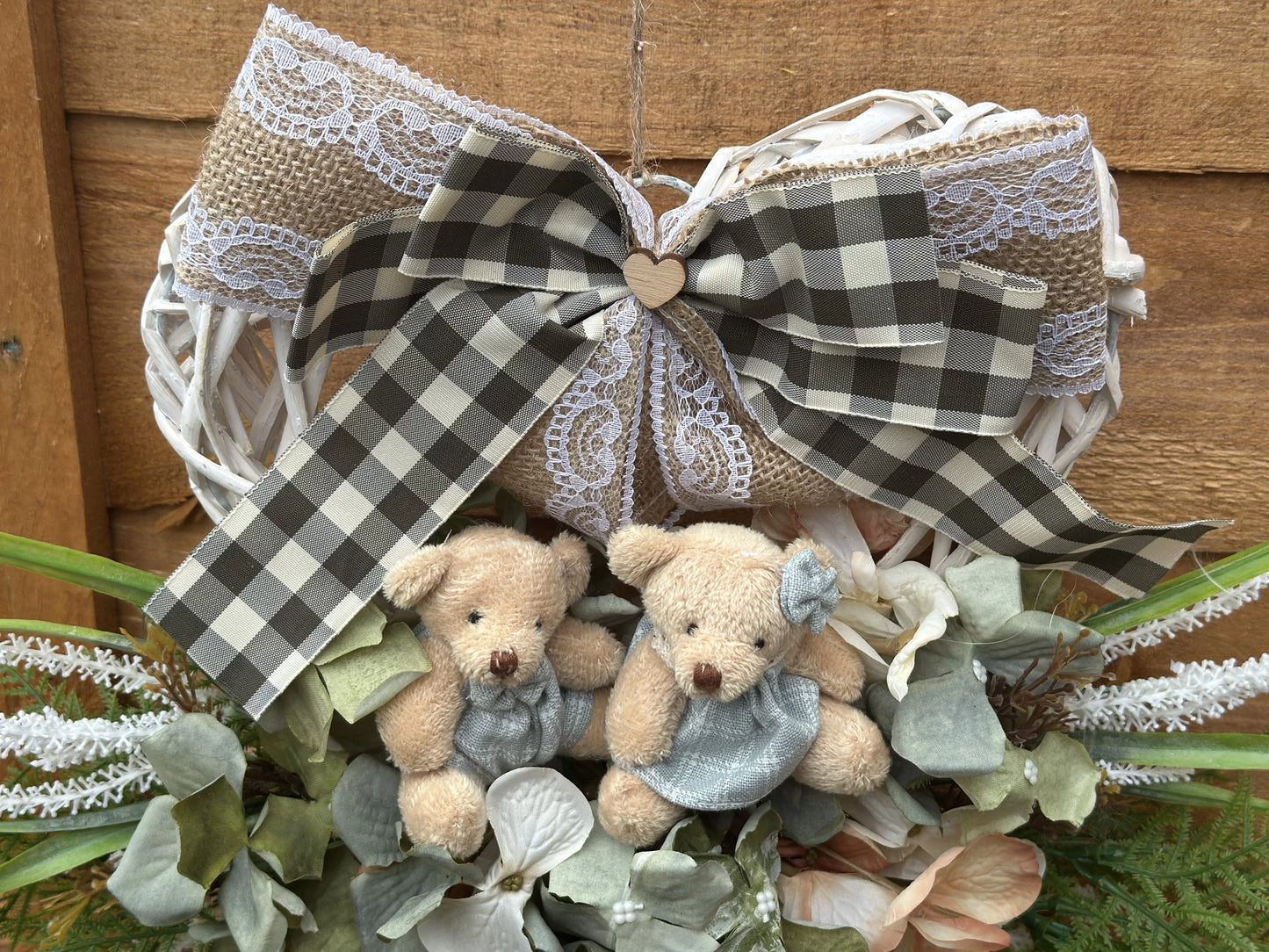 "Handmade heart-shaped wreath with teddy bears, artificial flowers, and a rustic burlap bow. Vintage-style home decor, perfect for housewarming gifts, nursery decoration, and front door wreaths. Romantic and family-inspired wooden wreath for indoor and outdoor use."