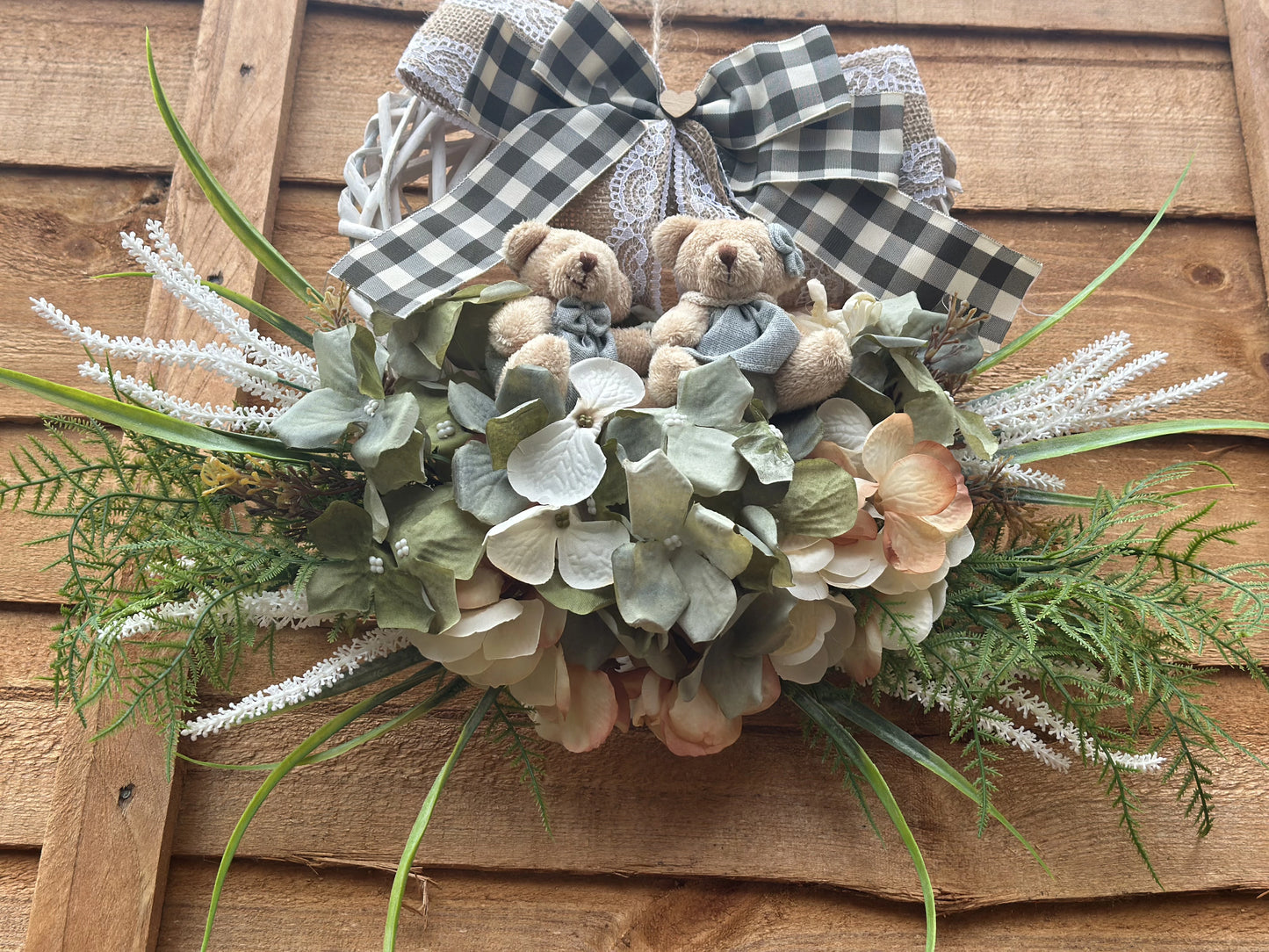 "Handmade heart-shaped wreath with teddy bears, artificial flowers, and a rustic burlap bow. Vintage-style home decor, perfect for housewarming gifts, nursery decoration, and front door wreaths. Romantic and family-inspired wooden wreath for indoor and outdoor use."