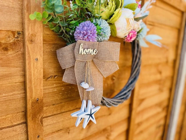 Summer door wreath with wooden base, fabric bow, and coastal accents.