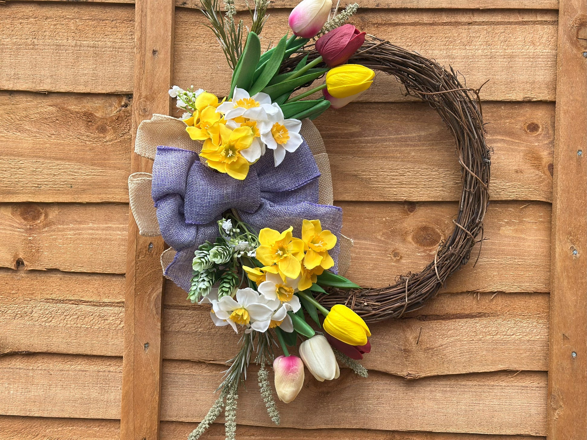 handmade wreath with seasonal artificial flowers and fairy ornament.