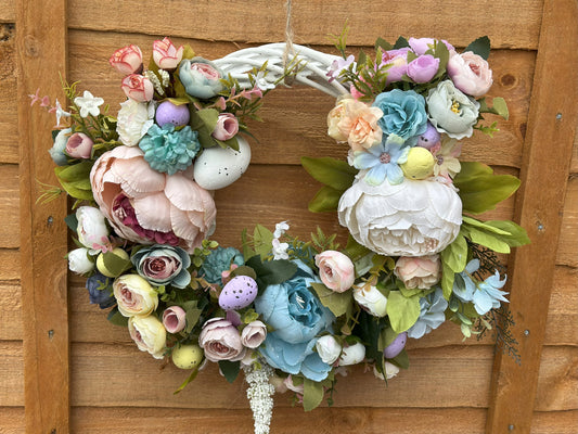 Handmade vintage floral wreath with artificial flowers in pastel colors, designed for door and wall decoration. Elegant spring-summer home décor with a romantic, luxurious touch."