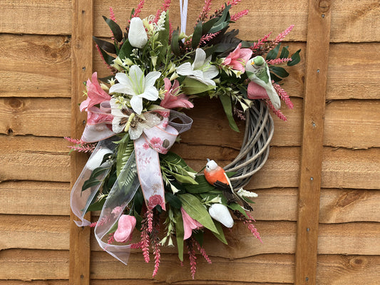Handmade spring wreath with pink and white artificial flowers, a floral ribbon, a decorative butterfly, and a rustic woven twig base. Perfect for front doors, walls, and seasonal home decor.