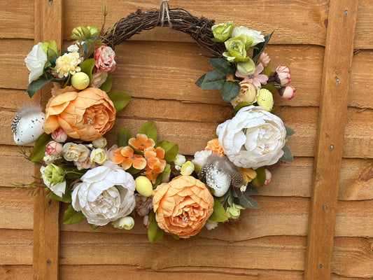 Handmade Easter wreath featuring artificial peonies, decorative eggs, and soft feathers – perfect spring home decor.